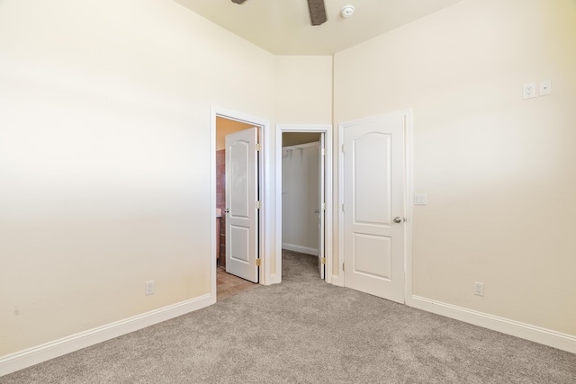 unfurnished bedroom featuring ceiling fan, light colored carpet, and a high ceiling