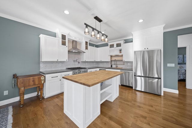 kitchen featuring wooden counters, wall chimney range hood, a center island, stainless steel appliances, and white cabinets