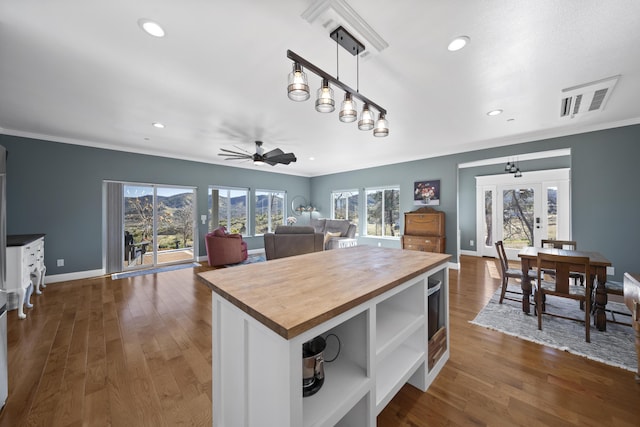 kitchen featuring ceiling fan, a center island, pendant lighting, dark hardwood / wood-style flooring, and butcher block counters