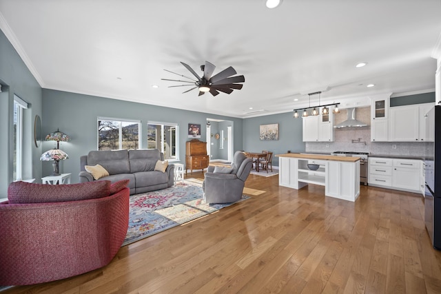 living room with ceiling fan, light hardwood / wood-style flooring, and ornamental molding