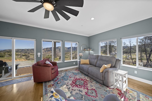 living room with a wealth of natural light, wood-type flooring, and ornamental molding