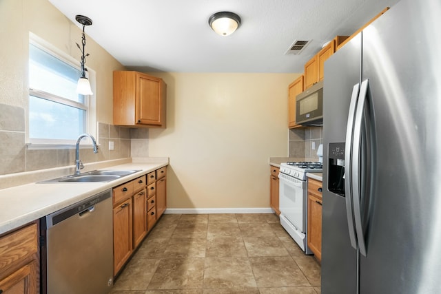 kitchen with decorative light fixtures, backsplash, stainless steel appliances, and sink