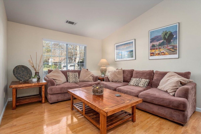 living room featuring lofted ceiling and light hardwood / wood-style floors