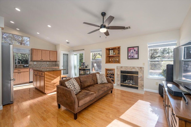 living room with vaulted ceiling, a high end fireplace, light hardwood / wood-style floors, ceiling fan, and sink