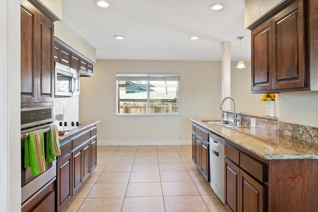 kitchen with appliances with stainless steel finishes, ornate columns, dark brown cabinetry, sink, and decorative light fixtures