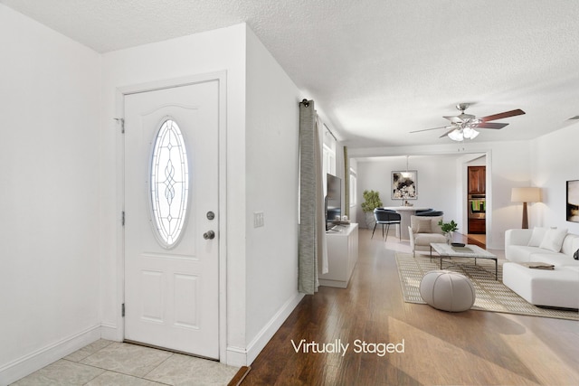 foyer entrance with ceiling fan and a textured ceiling