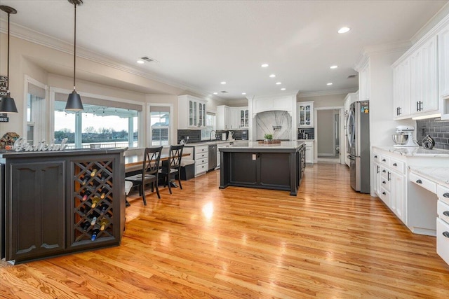 kitchen featuring white cabinetry, decorative backsplash, decorative light fixtures, stainless steel refrigerator, and a kitchen island