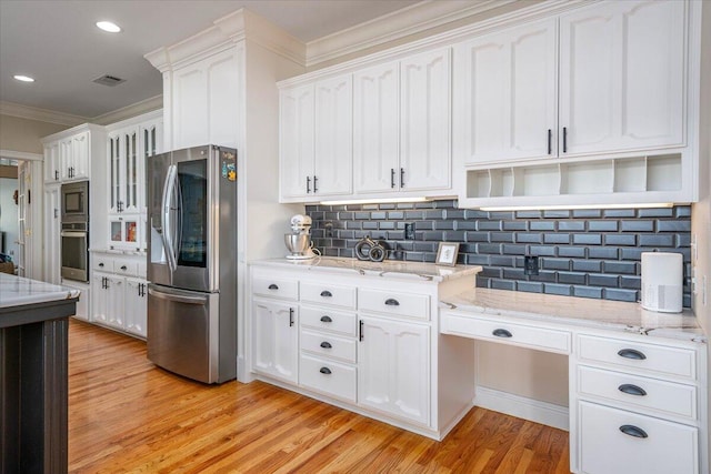 kitchen with white cabinetry, light hardwood / wood-style floors, appliances with stainless steel finishes, decorative backsplash, and crown molding