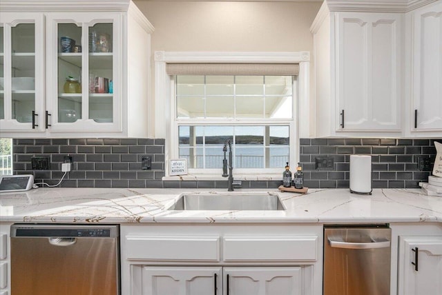 kitchen with light stone countertops, white cabinetry, tasteful backsplash, sink, and stainless steel dishwasher