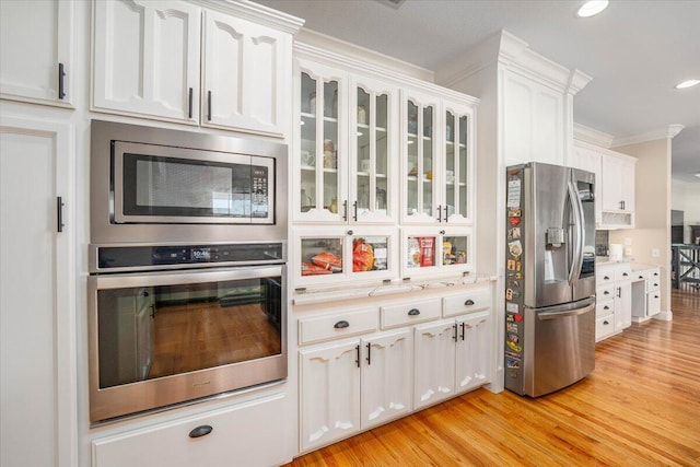 kitchen featuring white cabinetry, appliances with stainless steel finishes, light hardwood / wood-style flooring, and ornamental molding