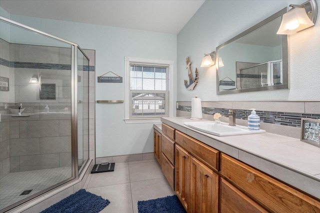 bathroom featuring a shower with door, tile patterned flooring, vanity, and tasteful backsplash