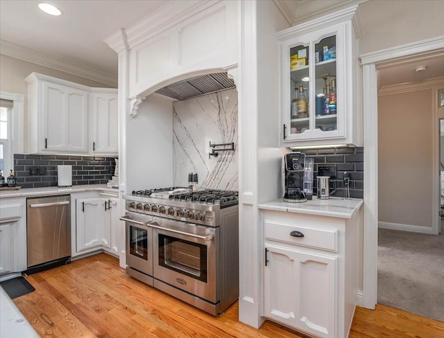 kitchen with white cabinets, stainless steel appliances, decorative backsplash, light hardwood / wood-style floors, and crown molding