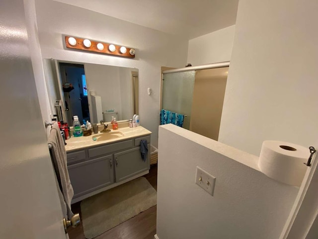 bathroom with walk in shower, vanity, toilet, and wood-type flooring