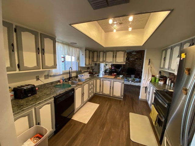 kitchen featuring dark wood-type flooring, stainless steel refrigerator, a tray ceiling, dishwasher, and range with electric cooktop