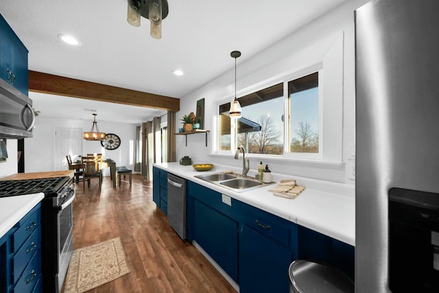 kitchen with sink, stainless steel appliances, decorative light fixtures, and blue cabinets