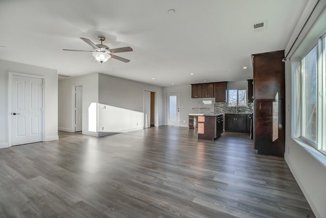 unfurnished living room featuring dark hardwood / wood-style flooring, ceiling fan, and sink