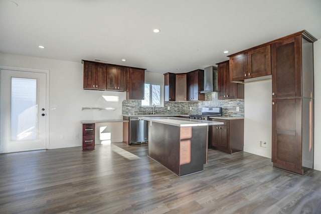 kitchen with a center island, hardwood / wood-style flooring, wall chimney exhaust hood, dark brown cabinetry, and stainless steel appliances