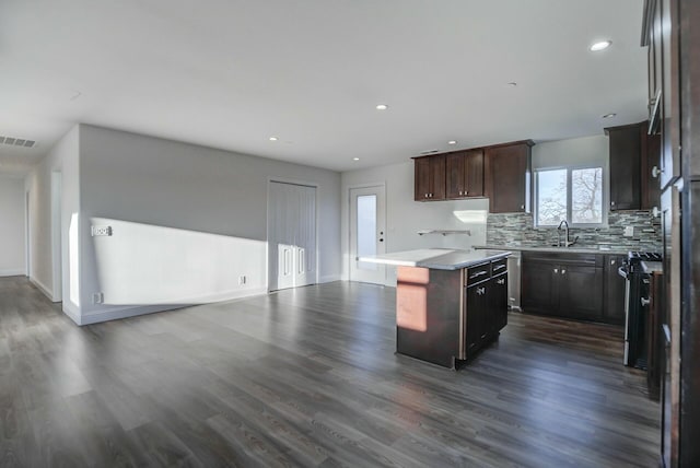 kitchen featuring dark brown cabinets, dark hardwood / wood-style floors, a kitchen island, and stainless steel stove