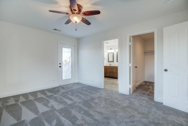 unfurnished bedroom featuring a walk in closet, ceiling fan, sink, carpet floors, and a closet