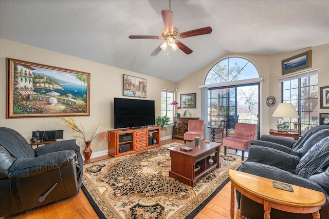 living room featuring a textured ceiling, vaulted ceiling, light hardwood / wood-style flooring, and ceiling fan