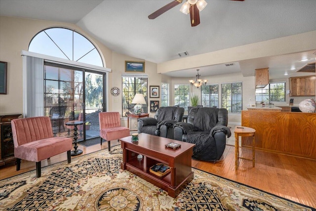 living room with a wealth of natural light, ceiling fan with notable chandelier, and hardwood / wood-style flooring