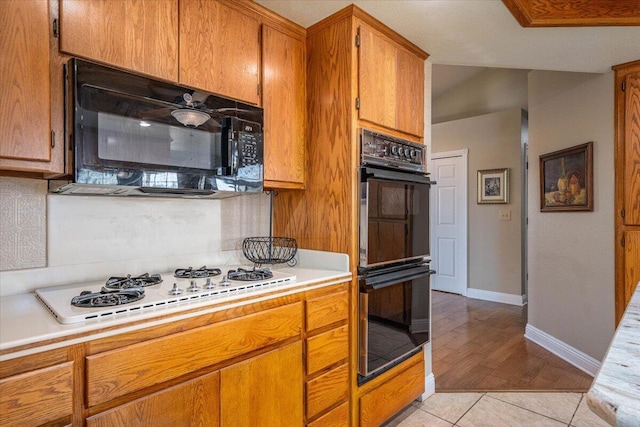 kitchen featuring black appliances, light tile patterned flooring, and tasteful backsplash