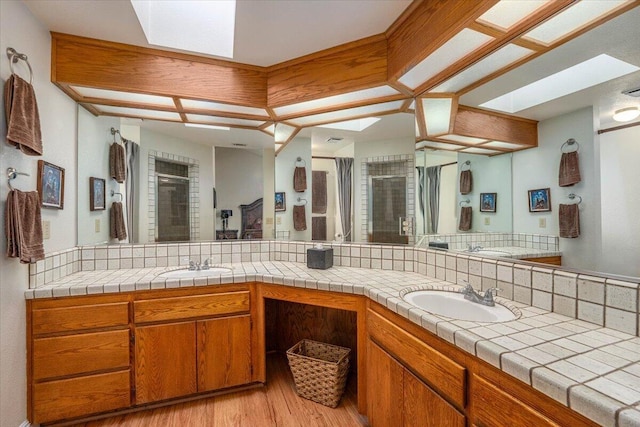 bathroom with hardwood / wood-style floors, vanity, an enclosed shower, and a skylight