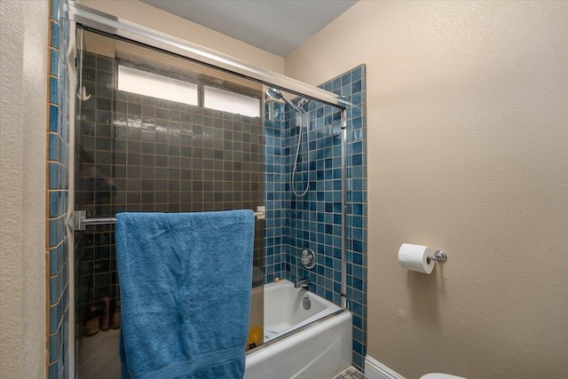 bathroom with toilet and combined bath / shower with glass door