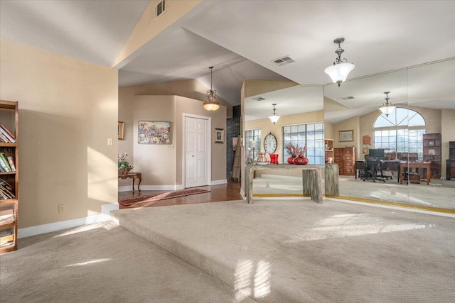 interior space featuring carpet, hanging light fixtures, and vaulted ceiling