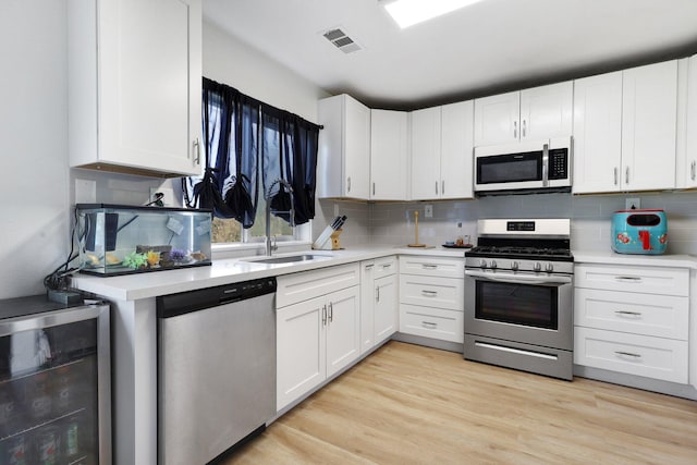 kitchen featuring wine cooler, appliances with stainless steel finishes, sink, and white cabinets