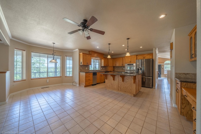 kitchen with stainless steel appliances, ceiling fan, crown molding, a kitchen island, and light tile patterned flooring