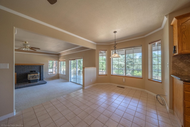 unfurnished dining area featuring light carpet, a wood stove, ceiling fan, and ornamental molding