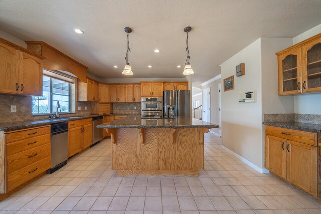 kitchen with sink, a center island, hanging light fixtures, tasteful backsplash, and appliances with stainless steel finishes