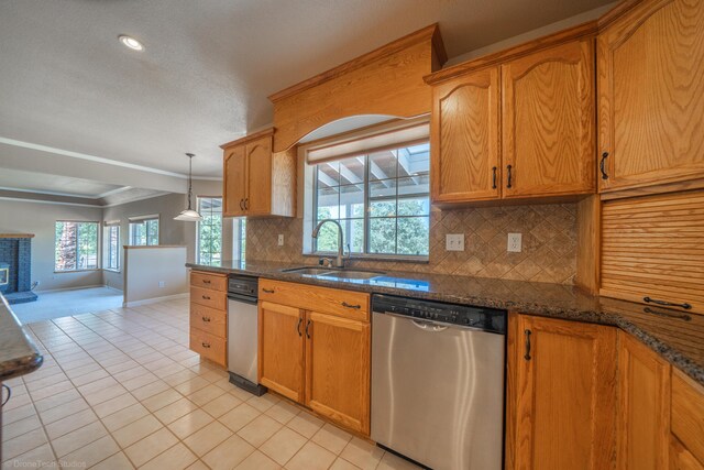 kitchen featuring backsplash, sink, stainless steel dishwasher, and decorative light fixtures