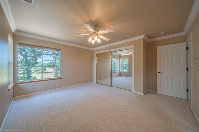 unfurnished bedroom with multiple windows, a closet, ceiling fan, and ornamental molding