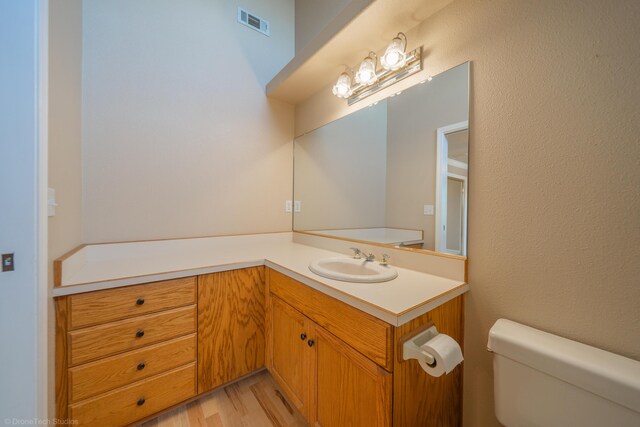 bathroom featuring vanity, hardwood / wood-style flooring, and toilet