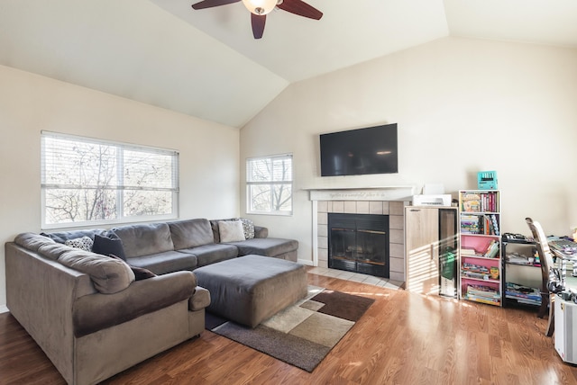 living room featuring a tile fireplace, a wealth of natural light, vaulted ceiling, and hardwood / wood-style flooring