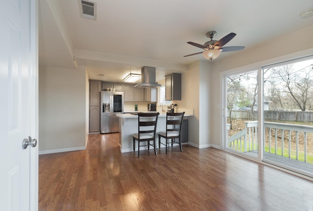 kitchen with ceiling fan, dark hardwood / wood-style floors, kitchen peninsula, stainless steel fridge, and island range hood