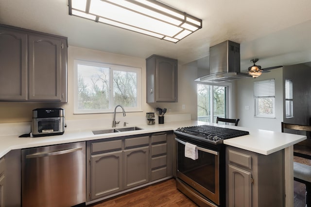 kitchen with ceiling fan, sink, stainless steel appliances, kitchen peninsula, and island exhaust hood