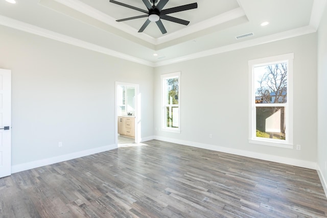 unfurnished room with ceiling fan, a tray ceiling, dark hardwood / wood-style flooring, and crown molding