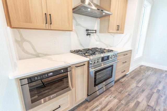 kitchen with hardwood / wood-style floors, high end range, light brown cabinets, wall oven, and ventilation hood