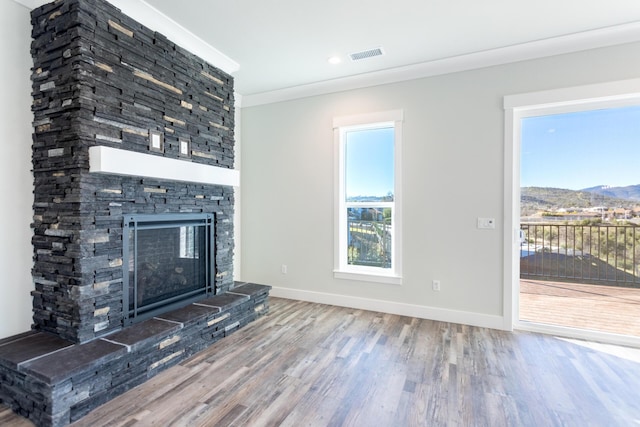 unfurnished living room featuring a mountain view, hardwood / wood-style floors, crown molding, and a fireplace