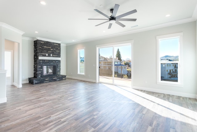 unfurnished living room featuring ceiling fan, crown molding, a fireplace, and light hardwood / wood-style flooring