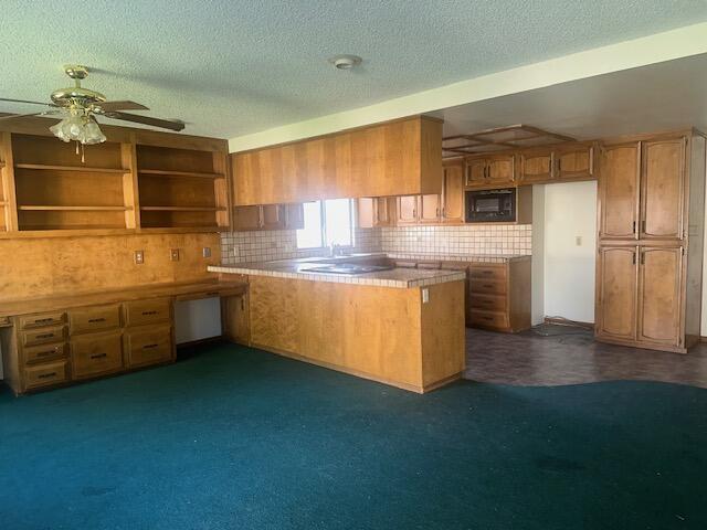 kitchen with tasteful backsplash, built in desk, a textured ceiling, black microwave, and kitchen peninsula