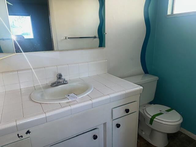 bathroom featuring vanity, toilet, and backsplash