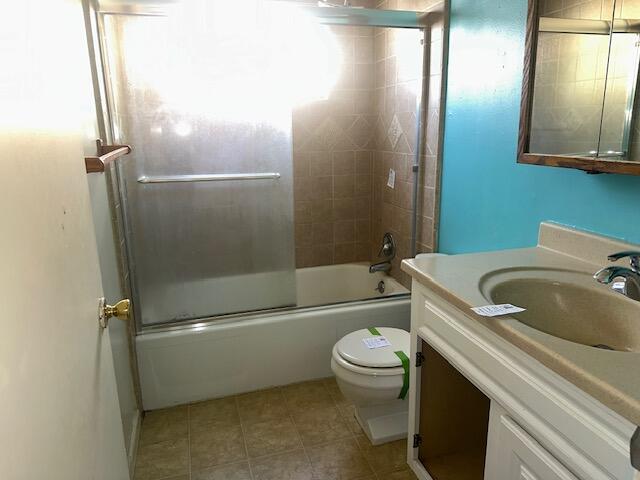 full bathroom featuring vanity, tile patterned flooring, bath / shower combo with glass door, and toilet