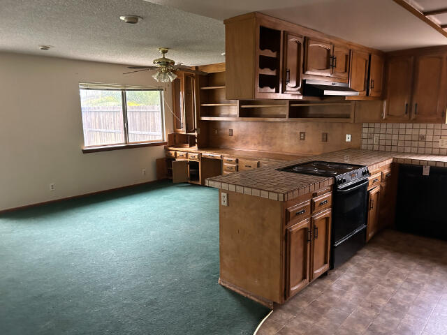 kitchen featuring tasteful backsplash, a textured ceiling, electric range, kitchen peninsula, and ceiling fan