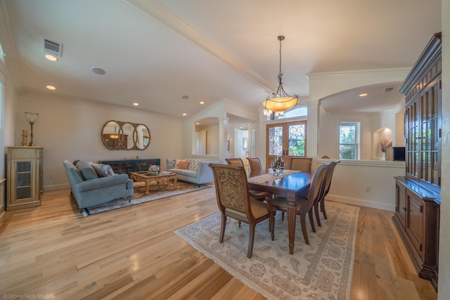 dining space featuring decorative columns, light hardwood / wood-style flooring, and ornamental molding