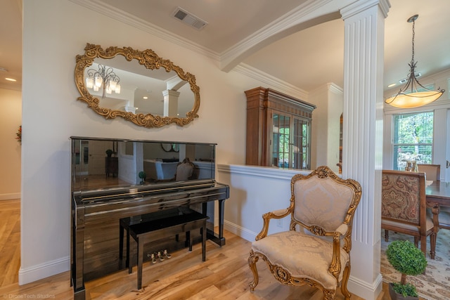 sitting room featuring decorative columns, light hardwood / wood-style floors, and ornamental molding