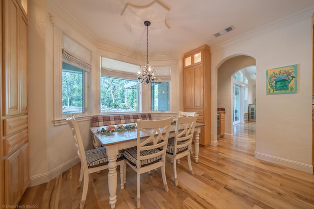 dining area featuring a notable chandelier, ornamental molding, and light hardwood / wood-style flooring